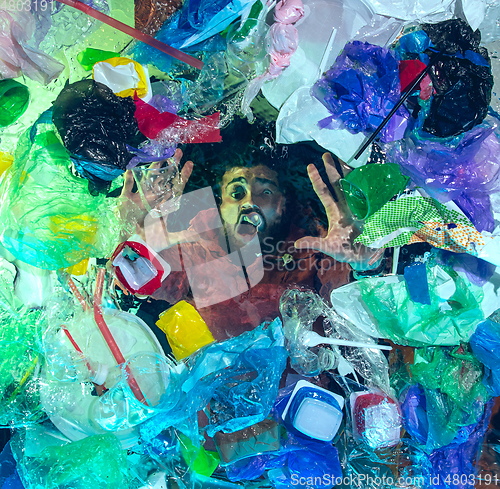 Image of Man drowning in ocean water under plastic recipients pile, environment concept