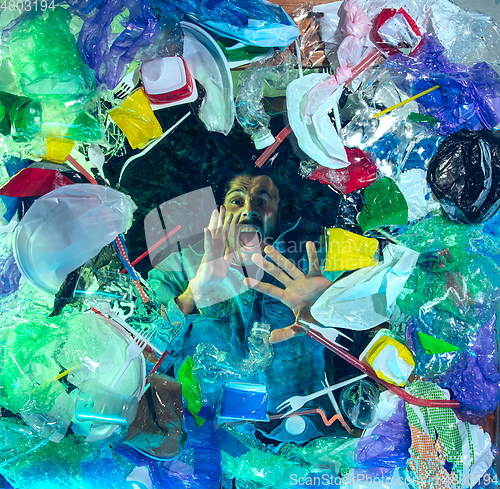 Image of Man drowning in ocean water under plastic recipients pile, environment concept