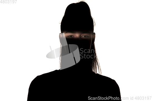 Image of Dramatic portrait of a girl in the dark on white studio background.