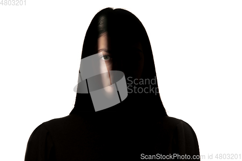 Image of Dramatic portrait of a girl in the dark on white studio background.