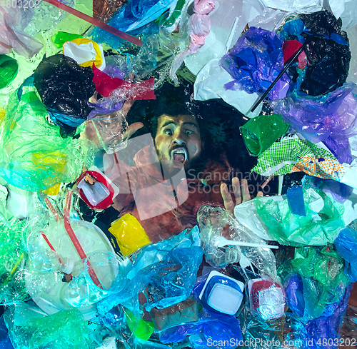 Image of Man drowning in ocean water under plastic recipients pile, environment concept