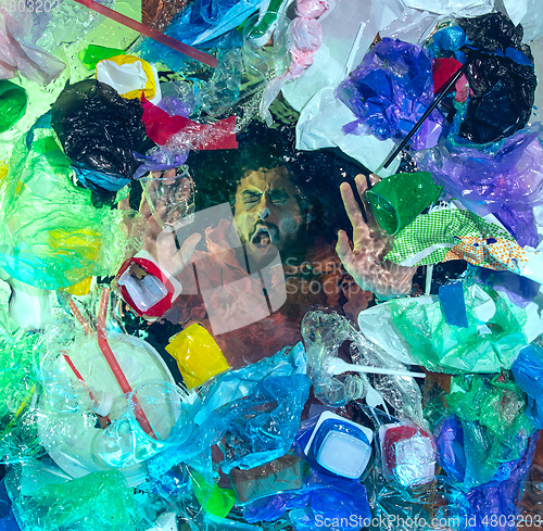 Image of Man drowning in ocean water under plastic recipients pile, environment concept