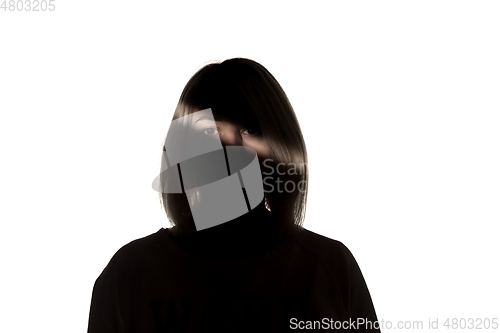 Image of Dramatic portrait of a girl in the dark on white studio background.