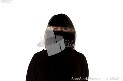 Image of Dramatic portrait of a girl in the dark on white studio background.