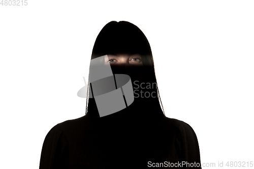 Image of Dramatic portrait of a girl in the dark on white studio background.