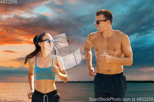 Image of couple in sports clothes running along over sea