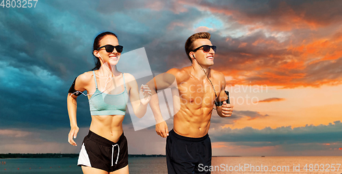 Image of couple with phones and arm bands running over sea