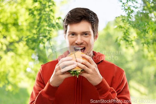 Image of happy young man eating hamburger