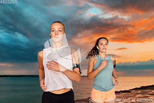 Image of young women with earphones and smartphones running