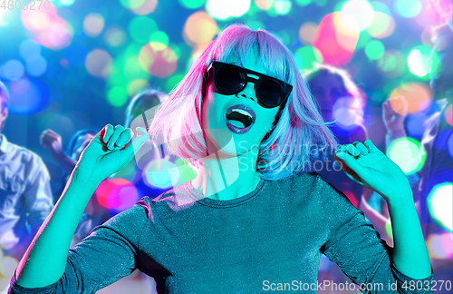 Image of woman in wig and sunglasses dancing at nightclub