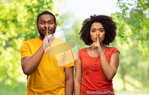 Image of happy african american couple making hush gesture