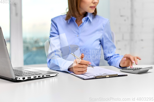 Image of businesswoman with papers, laptop and calculator