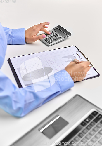 Image of businesswoman with papers, laptop and calculator