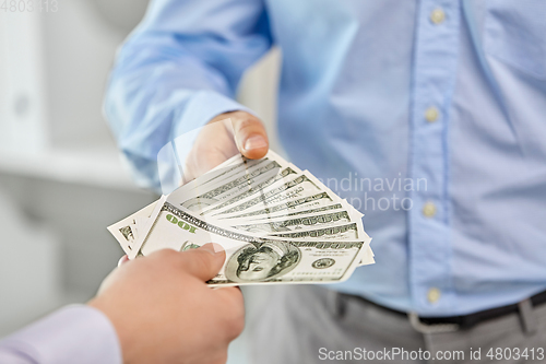 Image of close up of businessmen's hands holding money