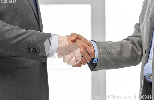 Image of close up of businessmen making handshake at office