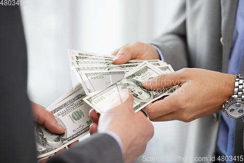 Image of close up of businessmen's hands holding money