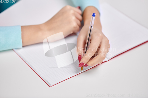 Image of hands of student girl with pen writing to notebook