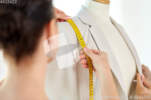 Image of fashion designer measures jacket with tape measure