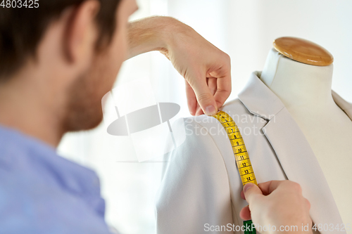 Image of fashion designer measures jacket with tape measure