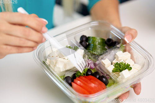 Image of hands of woman eating take out food from container