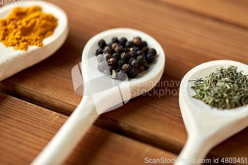Image of spoons with different spices on wooden table