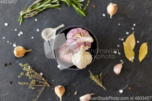 Image of garlic in bowl and rosemary on stone surface