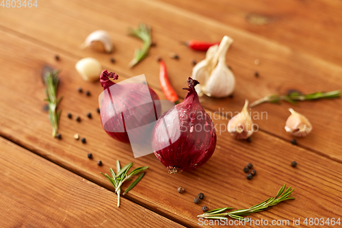 Image of onion, garlic, chili pepper and rosemary on table