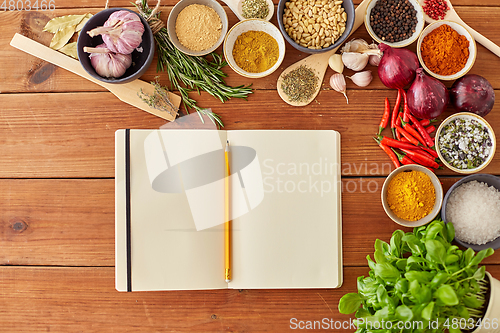 Image of notebook with pencil among spices on wooden table