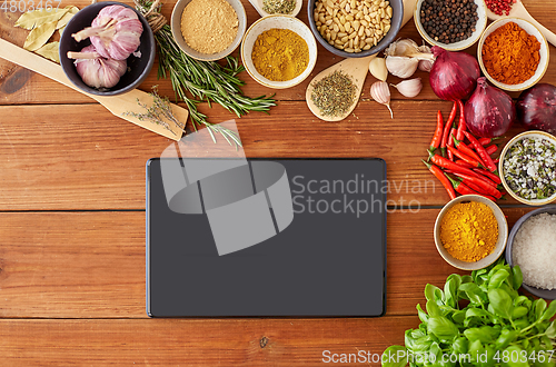 Image of tablet pc computer among spices on wooden table