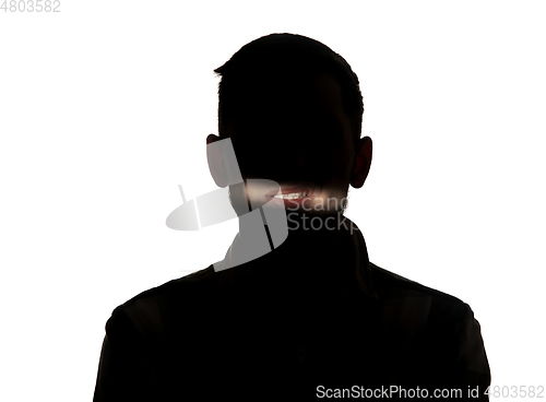 Image of Dramatic portrait of a man in the dark on white studio background.