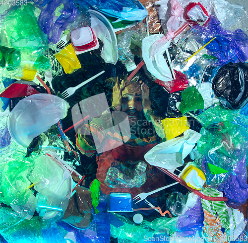 Image of Man drowning in ocean water under plastic recipients pile, environment concept