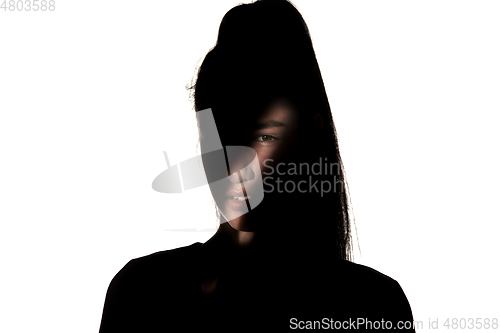 Image of Dramatic portrait of a girl in the dark on white studio background.