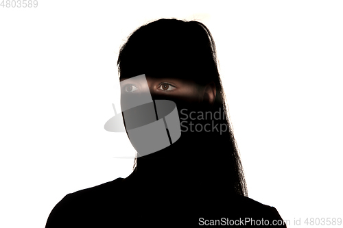 Image of Dramatic portrait of a girl in the dark on white studio background.