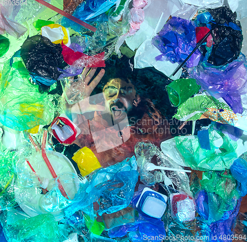 Image of Man drowning in ocean water under plastic recipients pile, environment concept