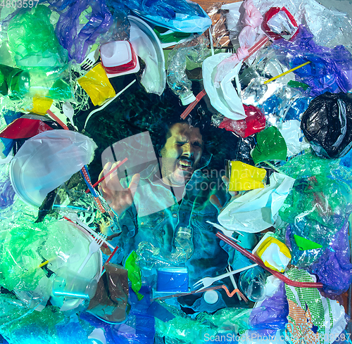 Image of Man drowning in ocean water under plastic recipients pile, environment concept