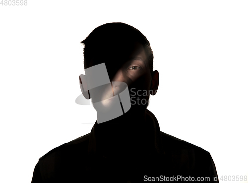 Image of Dramatic portrait of a man in the dark on white studio background.