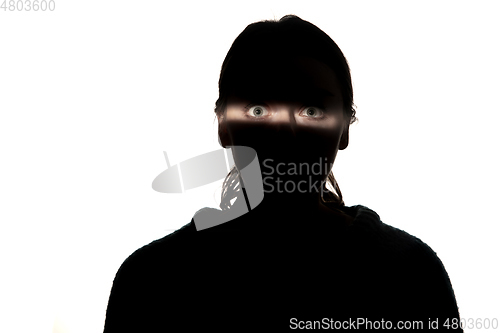 Image of Dramatic portrait of a girl in the dark on white studio background.