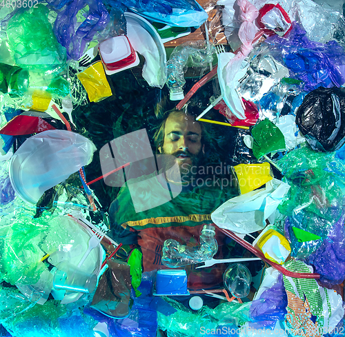 Image of Man drowning in ocean water under plastic recipients pile, environment concept