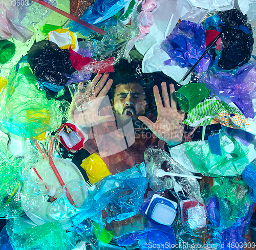 Image of Man drowning in ocean water under plastic recipients pile, environment concept