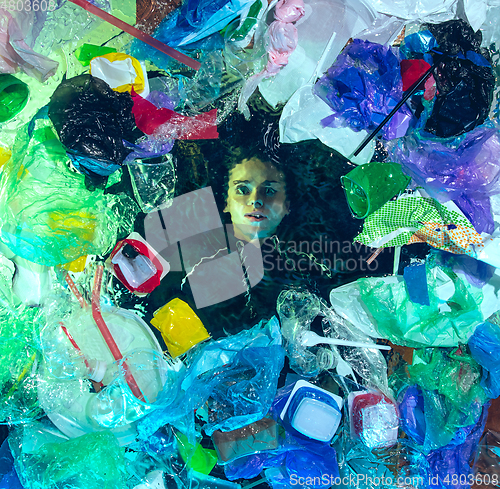 Image of Woman drowning in ocean water under plastic recipients pile, environment concept