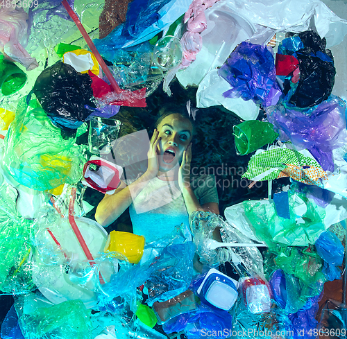 Image of Woman drowning in ocean water under plastic recipients pile, environment concept