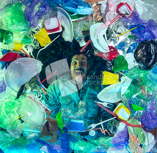 Image of Man drowning in ocean water under plastic recipients pile, environment concept