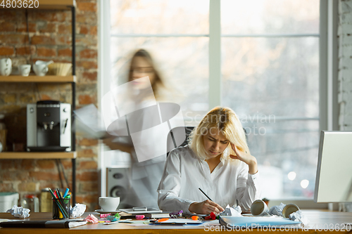 Image of Nervous and tired boss at her workplace busy while people moving near blurred