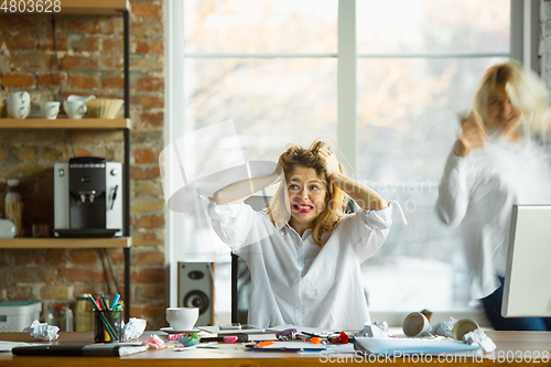 Image of Nervous and tired boss at her workplace busy while people moving near blurred