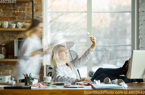 Image of Tired boss resting at her workplace while people moving near blurred