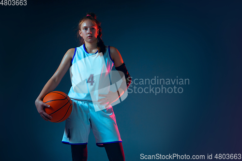 Image of Young caucasian female basketball player on blue studio background in neon light