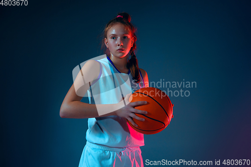 Image of Young caucasian female basketball player on blue studio background in neon light