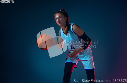 Image of Young caucasian female basketball player on blue studio background in neon light