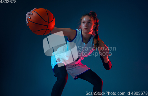 Image of Young caucasian female basketball player on blue studio background in neon light