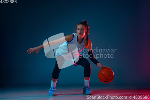 Image of Young caucasian female basketball player on blue studio background in neon light
